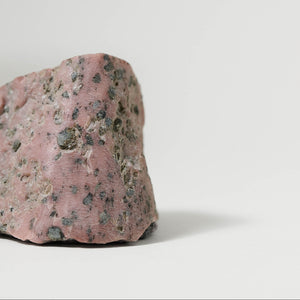 Pink rock with dark spots on a white background